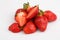 Isolated close up top view shot of a bunch of whole and sliced in half vibrant red strawberries on a white background