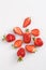 Isolated close up top view shot of a bunch of whole and sliced in half vibrant red strawberries on a white background