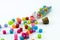 Isolated colourful small cubes with characters scattered from the vial on white background.