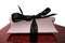 Isolated gift box with black ribbon on red glittery pad background