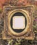 Isolated golden tintype picture frame. Old tintype frame in center surrounded by modern oval frame with embossed floral design.