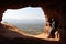 ISOLATED HERMIT MAN WITH DJELLABA AND PALESTINIAN SCARF SITTING AT THE ENTRANCE OF A CAVE ON THE HIGH OF A MOUNTAIN