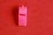 Isolated high angle top view closeup shot of a pink whistle toy on a red table