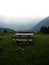 Isolated idyllic remote wooden picnic table bench on green grass hill outdoor nature alpine mountain landscape alps