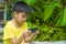 Isolated lifestyle portrait of 7 or 8 years old Asian child focused and concentrated playing with mobile phone outdoors at home
