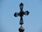 Isolated orthodox monastery church metal cross against blue sky.