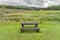 Isolated park bench in Wales countryside, with a view of a stormy sky