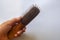 Isolated people hand hold wooden comb with hair fall and loss