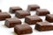 An isolated pile of milk chocolate slab blocks broken up and laid out in rows on a white background