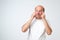 Isolated portrait of puzzled senior male looking up and holding fingers on his temples, trying to remember something