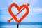 Isolated post signal with red love heart and arrow at beach on a blue sea and sky background in Valentines day and romance concept