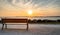 Isolated public bench at sunrise. Re island bridge in the background