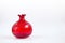Isolated red, pomegranate shaped glass object with white background.