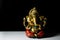 An isolated sculpture of the Indian god Ganesha placed on a reflective white table in a dark background