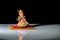 An isolated sculpture of Indian god lord Krishna playing flute sitting on a mat. On a reflective white table with a dark