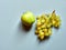 Isolated set of a green apple with a bunch of sweet seedless grapes in studio with blue background