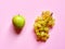 Isolated set of a green apple with a bunch of sweet seedless grapes in studio with millennial pink background