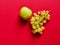 Isolated set of a green apple with a bunch of sweet seedless grapes in studio with red background