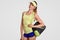 Isolated shot of cheerful satisfied female tennis player dressed in casual t shirt and shorts, holds bag with sport equipment, goe