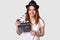 Isolated shot of cheerful woman director involved in sphere of cinematography, holds film clapper, dressed in casual t shirt and