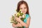 Isolated shot of pretty small girl preapres bouquet of flowers to mum on Mothers Day, has appealing appearance, dressed in festive