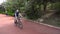 Isolated, skinny young male wearing a mask cycling on a bicycle path at a park