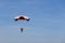 Isolated skydiver in colorful parachute gliding after free fall
