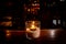 Isolated tealight inside a glass illuminating a dark scene and reflections on a wooden table and a nice bokeh background