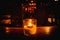 Isolated tealight inside a glass illuminating a dark scene and reflections on a wooden table and a nice bokeh background