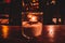 Isolated tealight inside a glass illuminating a dark scene and reflections on a wooden table and a nice bokeh background