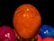 Isolated transformed single dark orange shining detailed textured easter egg on blurred colorful and black