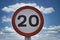 Isolated twenty speed limit sign against blue sky and white clouds background