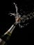 Isolated vertical shot of an opened champagne bottle with the cork in the air on a black background