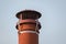 Isolated view of an old fashioned, terracotta chimney pot seen on a cottage roof, against a clear sky.