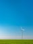 Isolated wind generator in green wheat field under blue sky