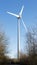 Isolated wind turbine surrounded by trees and a clear blue sky behind