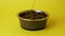 Isolated on yellow background of dry pet food or kibble being poured into an empty dish, bowl