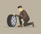 Isolated young male character sits down and checks the air pressure in his tire.