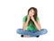 Isolated young reflective woman sitting with crossed legs.