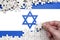 Israel flag is depicted on a table on which the human hand folds a puzzle of white color