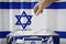Israel flag, hand dropping ballot card into a box - voting, election concept