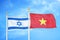 Israel and Vietnam two flags on flagpoles and blue cloudy sky