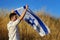 Israeli citizen Jewish patriot stands in a field and looks at the flag Israel in his hands in front of himself. Patriotic holiday