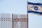 Israeli flag flying next to a fence on a clear sky day
