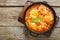 Israeli fried eggs shakshuk in a frying pan on a wooden table. copy space