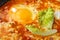 Israeli fried eggs shakshuka with cheese and sauce close-up