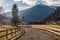 Italian Alps, asphalt road fenced with a wooden fence leading to alpine village