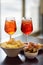 Italian aperitives/aperitif: glass of cocktail sparkling wine with Aperol and appetizer platter on the table