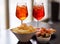 Italian aperitives/aperitif: glass of cocktail sparkling wine with Aperol and appetizer platter on the table