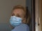 Italian blonde woman with protective mask forced to stay closed at home for the quarantine following the spread of the coronavirus